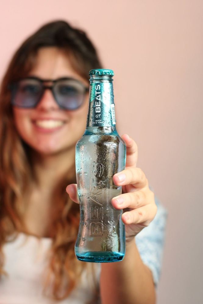 Modelo con una botella de Beats GT sobre fondo rosa